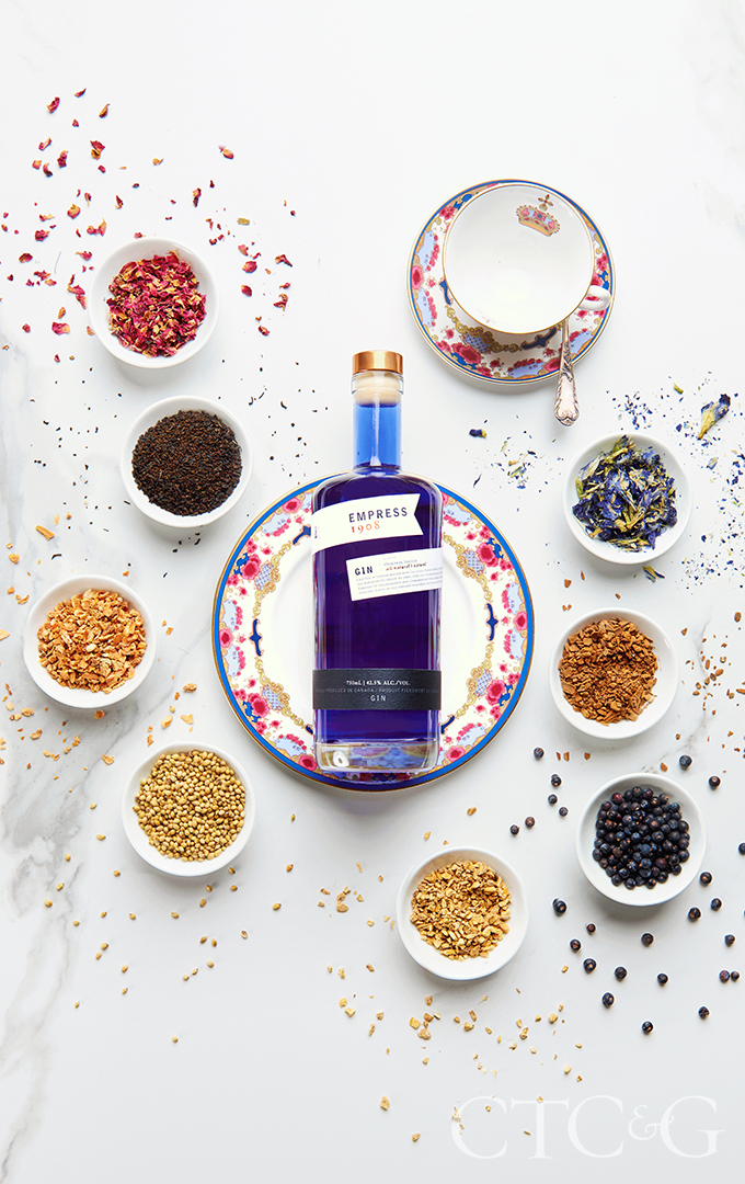 A royal blue gin bottle on a pink and blue plate.