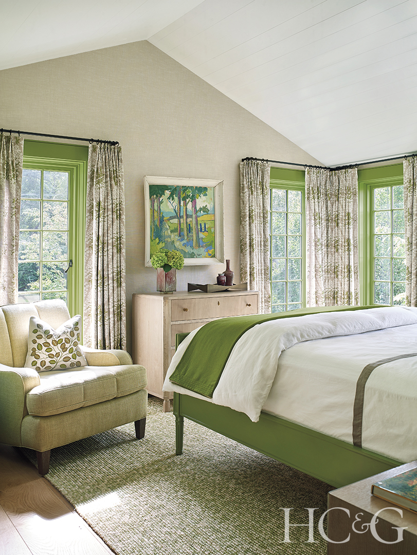 Full-length windows brighten up the white and green guest bedroom.