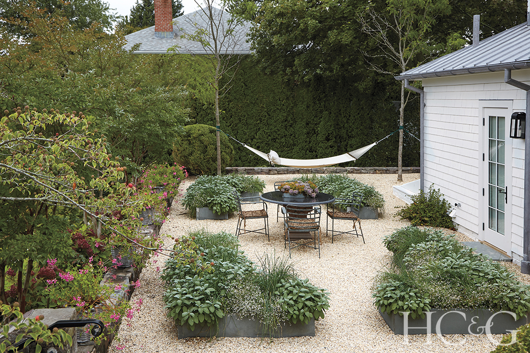 A hammock and outdoor dining set situated in a herb garden.