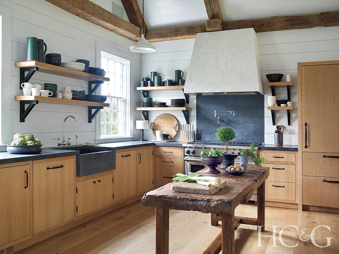 A white-walled kitchen with a wooden table, wooden cabinetry, and wooden flooring.