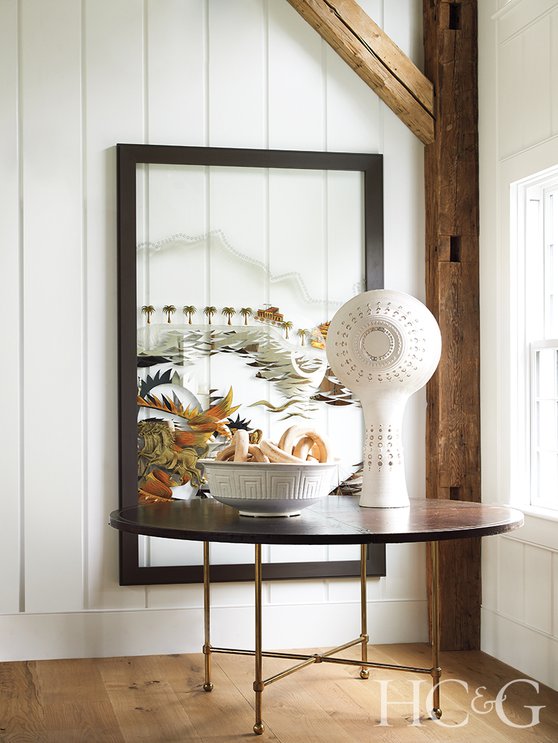 A white sculpture on a black table, in front of framed artwork.