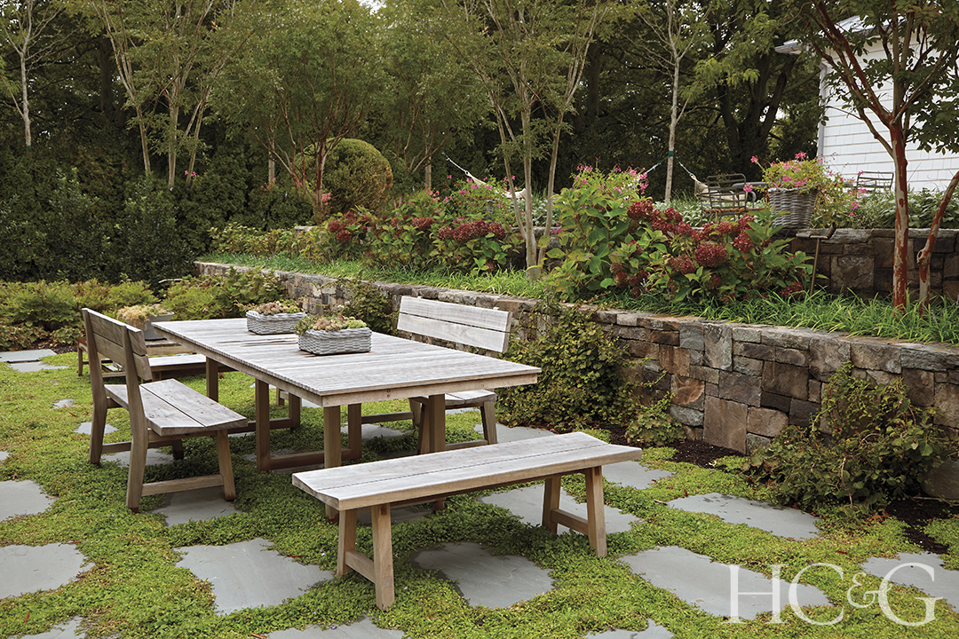 Wooden benches surround a wooden table outdoors.