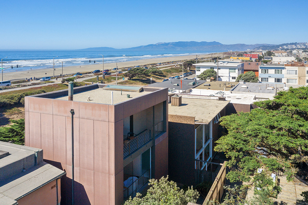 View of a midcentury home with the ocean behind it