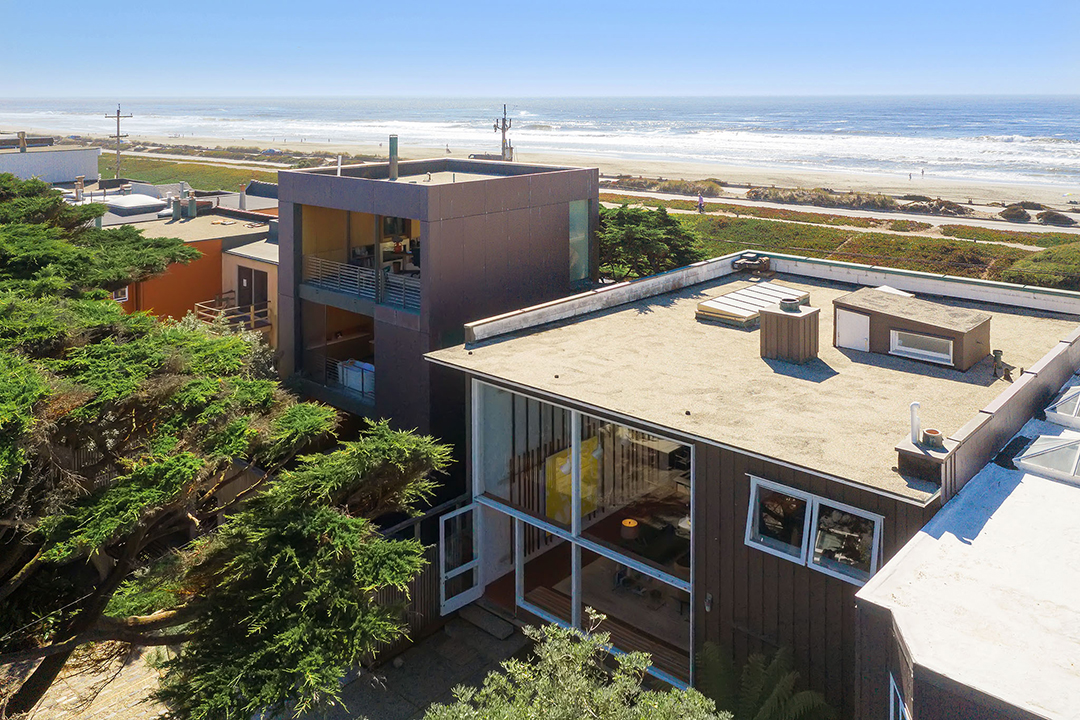 View of a midcentury home with the ocean behind it