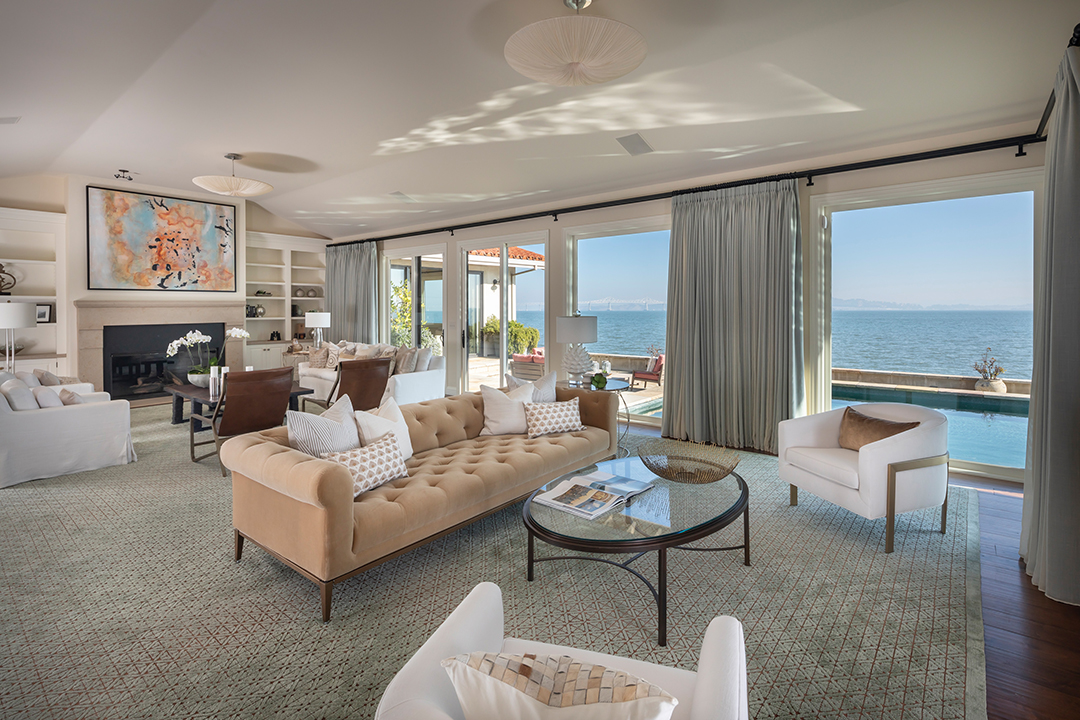 Large living room with walls of windows and water views