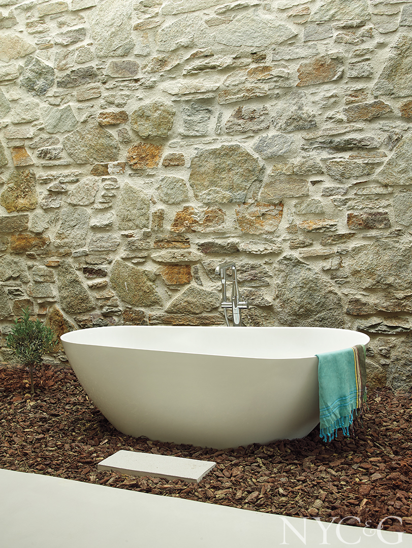 white bathtub set on stone gravel flooring