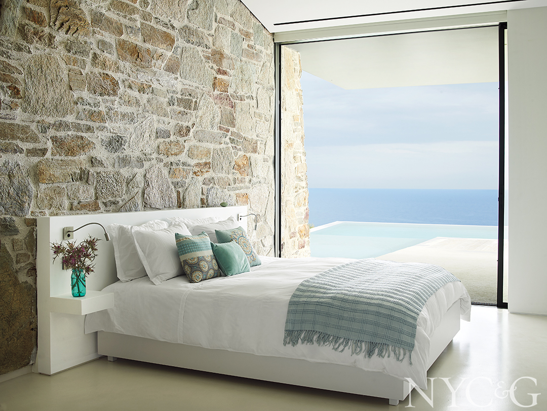 bedroom with white bedroom and turquoise throw overlooking pool and ocean