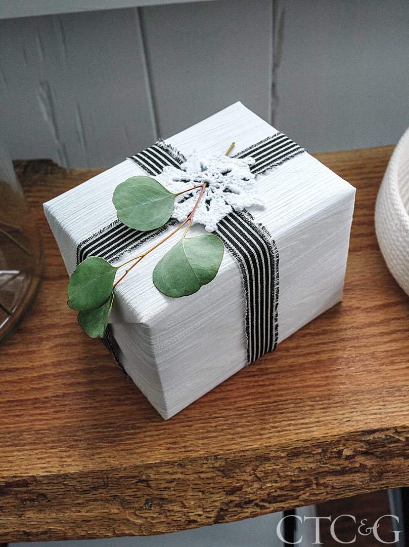 Christmas gift wrapped with striped ribbon and a sprig of eucalyptus leaf