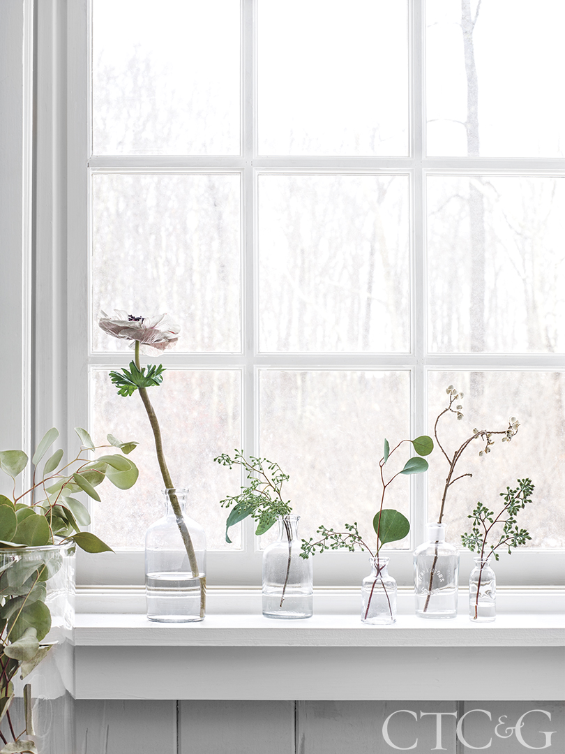 Flowers and cut branches in vases create a holiday windowsill display