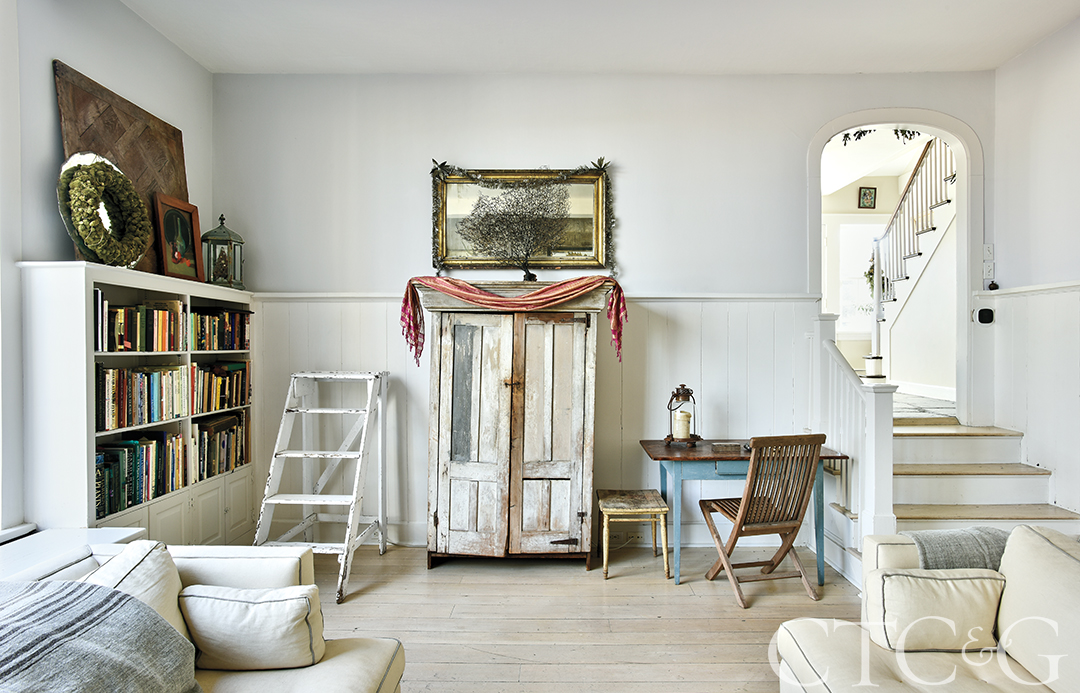 farmhouse living room with antique cupboard, bookshelves and desk