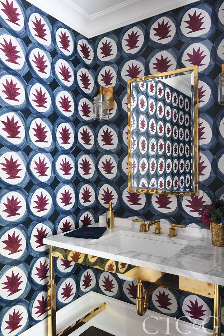 Powder room with colorful wallpaper and gold finishings.
