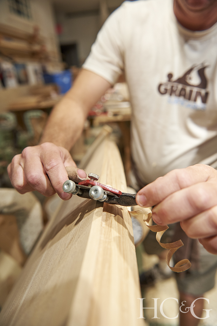 A spoke shave is used to shave a curling piece of wood.