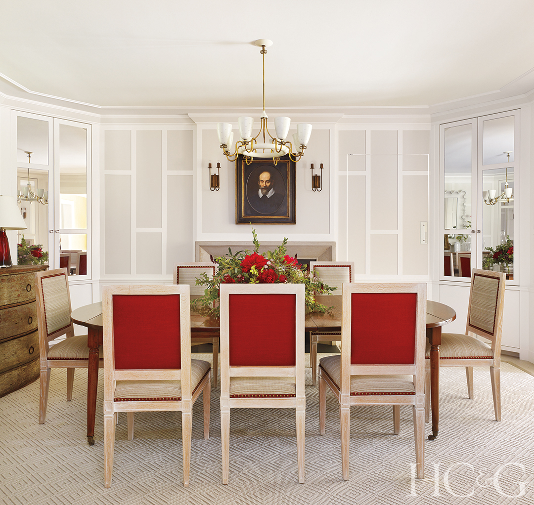 Three red chairs face a dining room table in a white room.