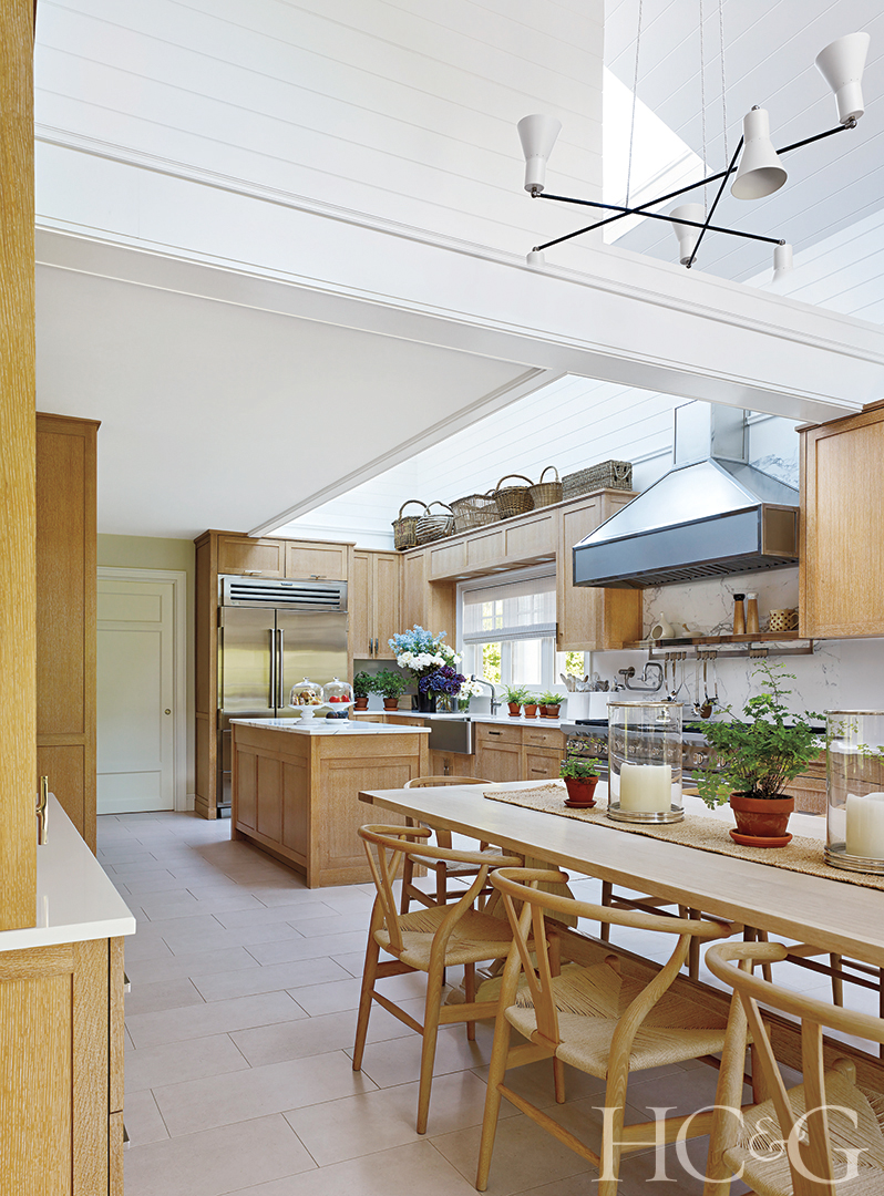 A kitchen with wooden tables and cabinetry, along with wicker chairs.