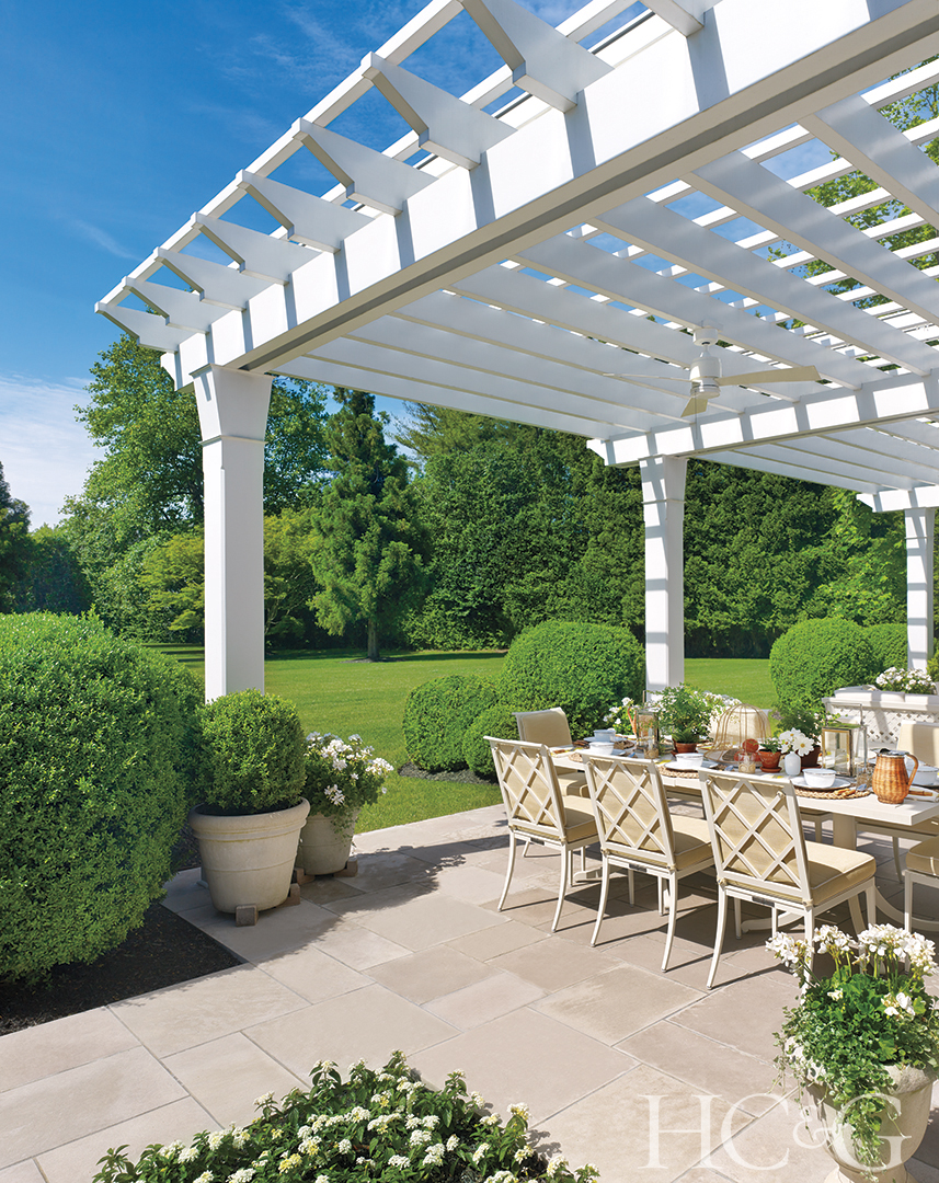 Blue skies and green grass are the background of a limestone terrace with a white overhang.