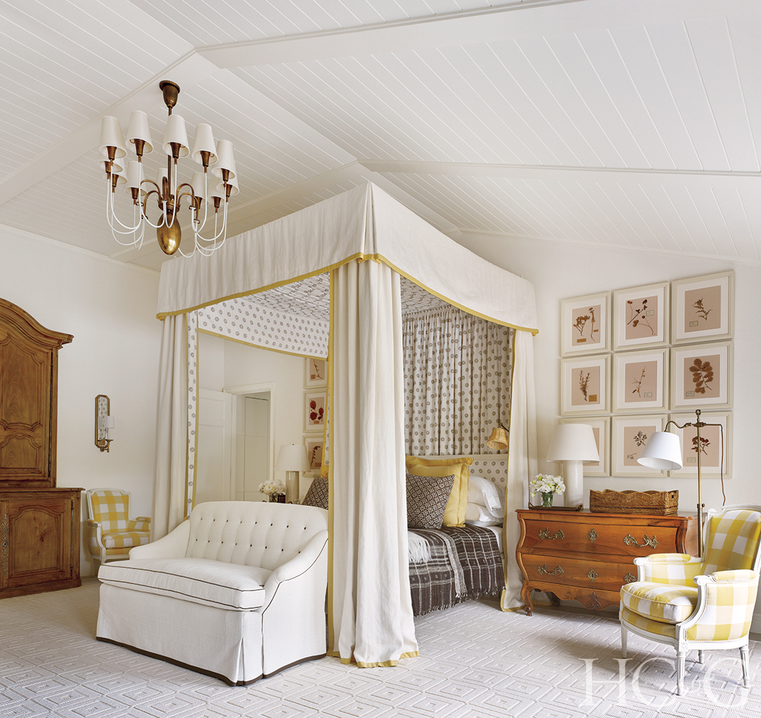 An elegant white canopy with gold trim hangs over a master bed.