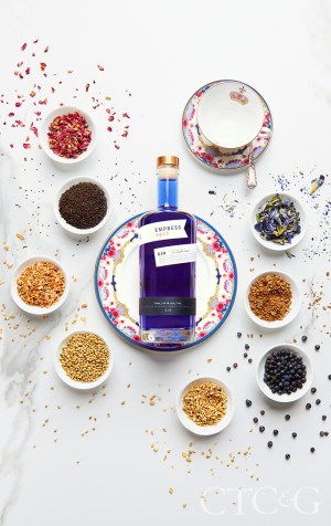 A royal blue gin bottle on a pink and blue plate.