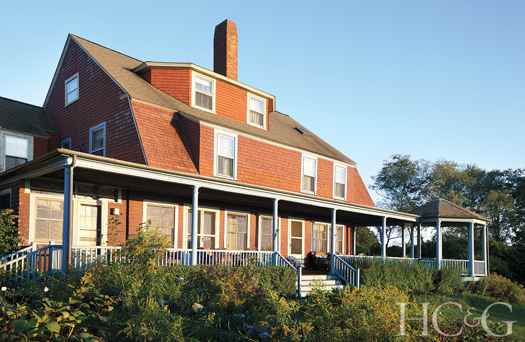 A multi-story orange shingle-style house faces the sun, surrounded by greenery.