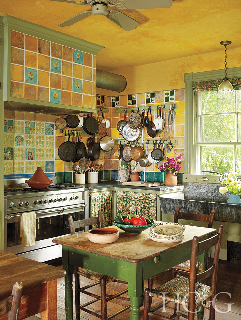 A yellow, green, and blue tiled kitchen with a green table in the center.