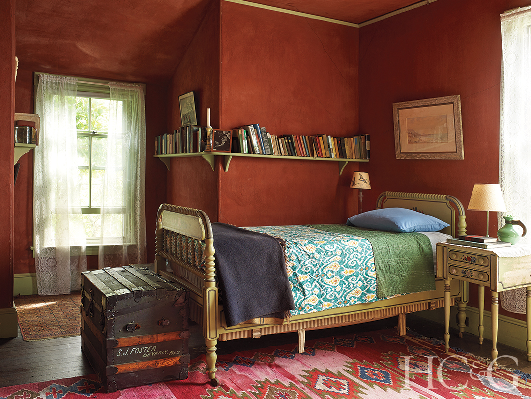 A blue twin bed in a red walled and carpeted floors.