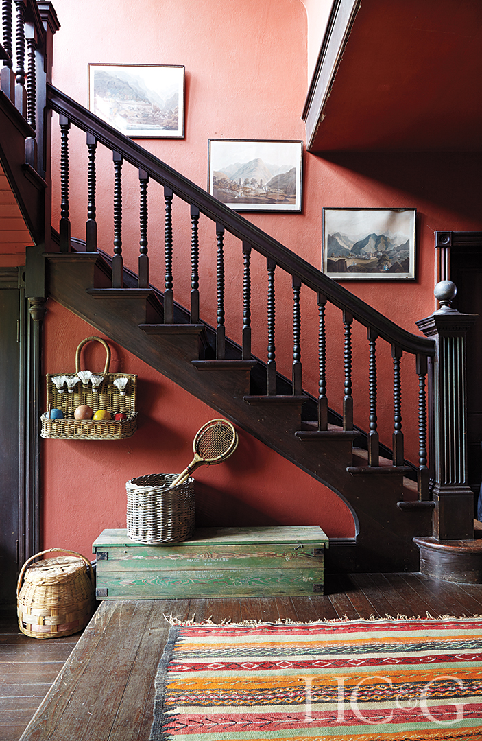 A dark staircase climbs up against a burnt red wall.