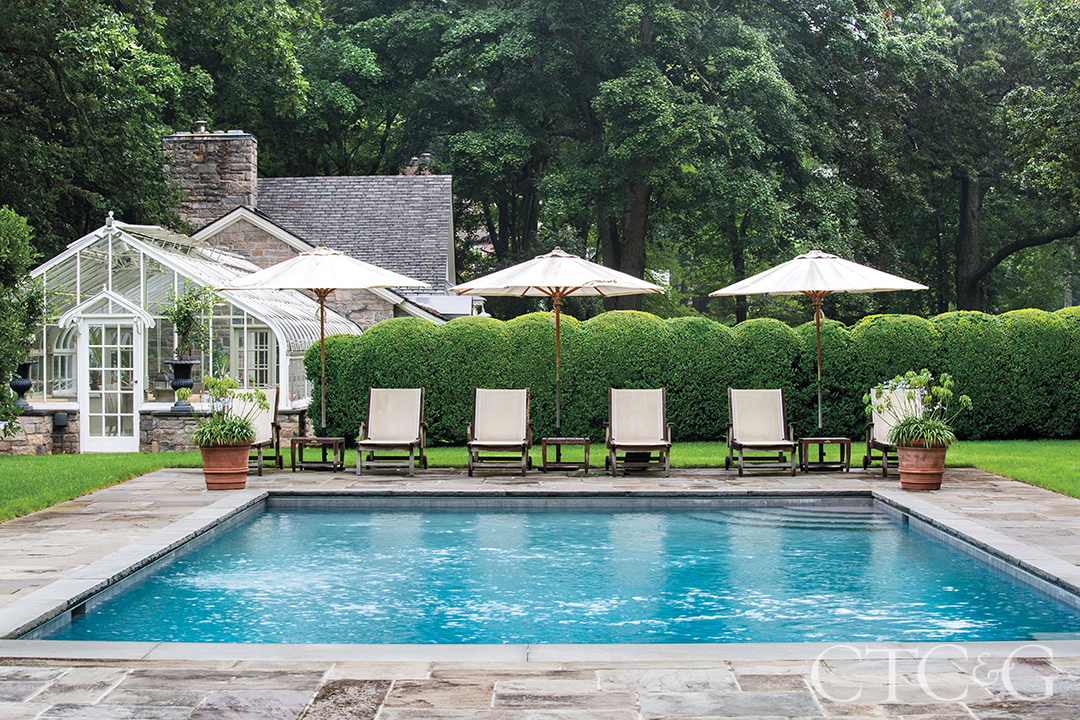 Four lounge chairs and three umbrellas sit poolside.