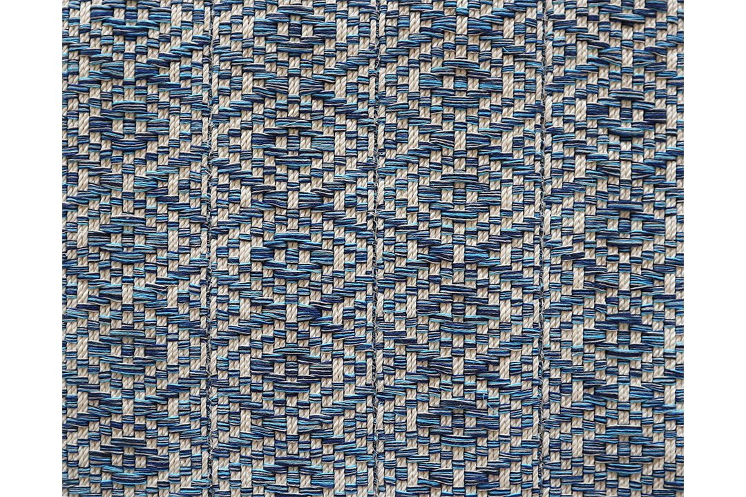 A blue and off-white woven rug in a diamond pattern,