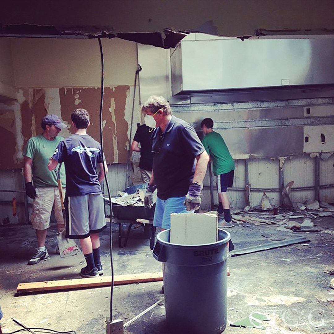 Five men working in a stripped room, with debris on the ground.