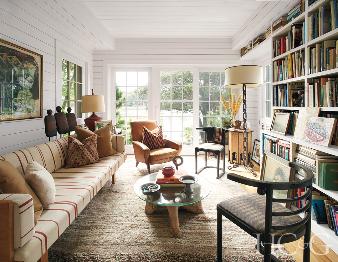 Backed by glass doors and white walls, a brown Berber carpet sits under a glass table, striped sofa, and chairs.