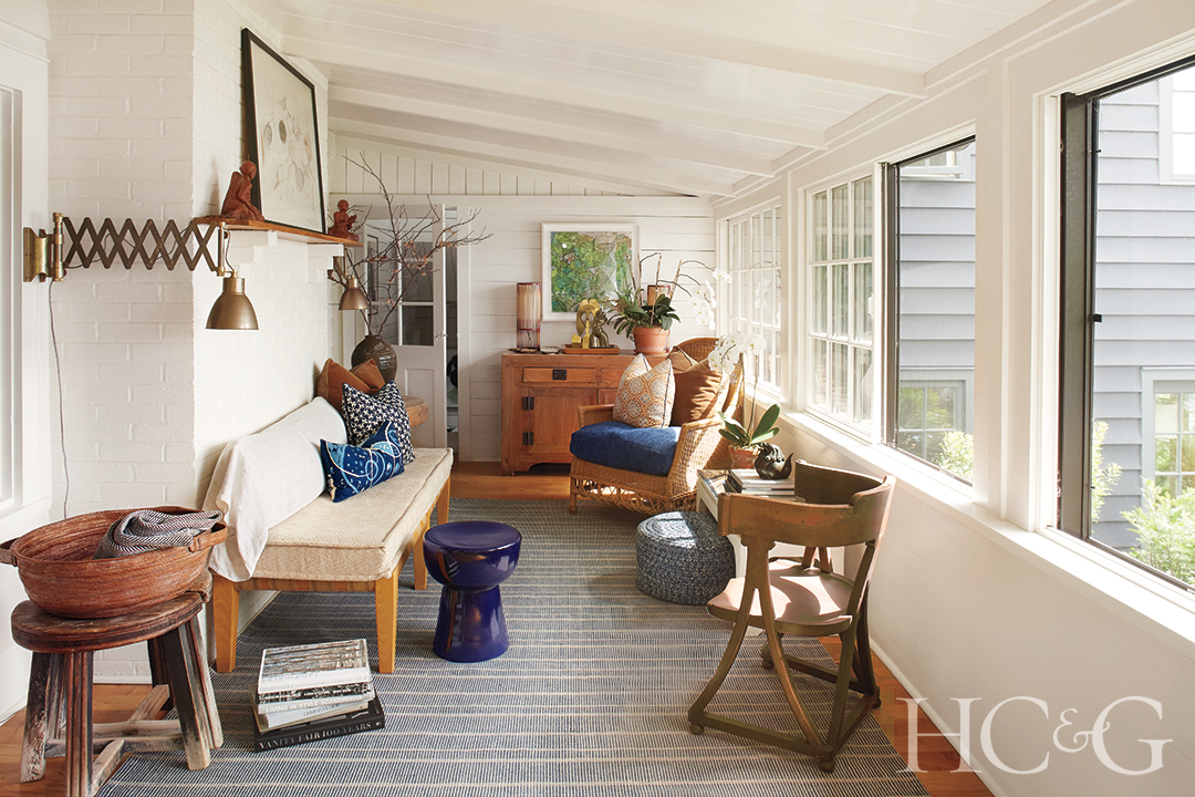 Lined with big bright windows on the right, the sun shines into this white room filled with wood furniture with pops of blue.