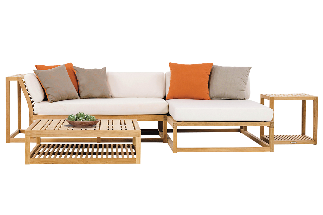 A teak lounge set featuring a white cushioned couch with orange and grey accent pillows, and two wood tables.