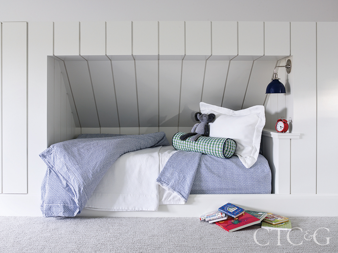 blue patterned quilt sits atop bed tucked into a nook in the bunk room