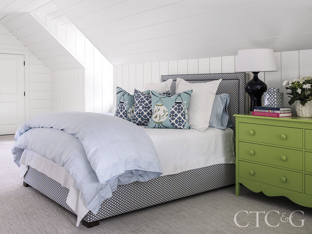 green chest sits next to blue patterned comforter and pillows atop custom bed in the bunk room