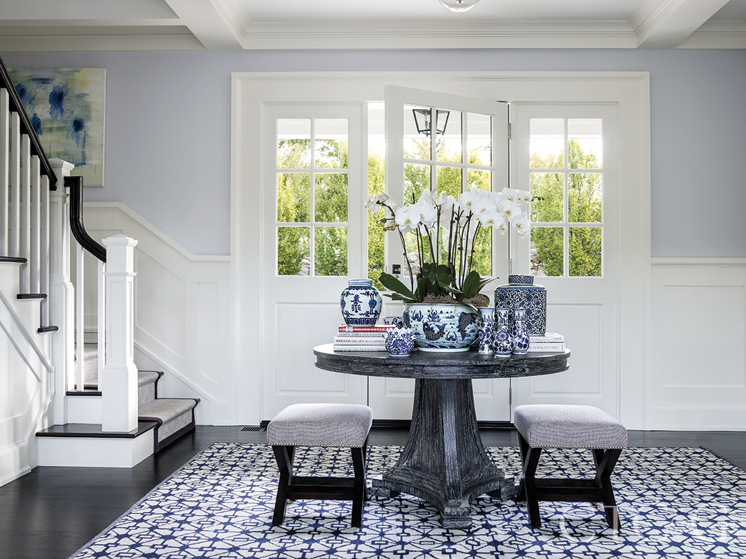 custom stools and cerused oak table and decor atop blue patterned rug create eye-catching entry