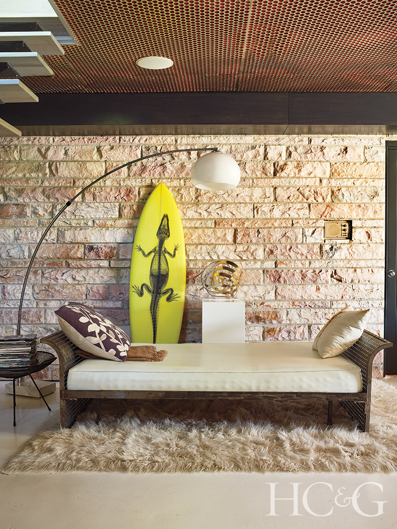 Vintage Metal Daybed and Overhead Lamp with Stone Wall and Yellow Surfboard