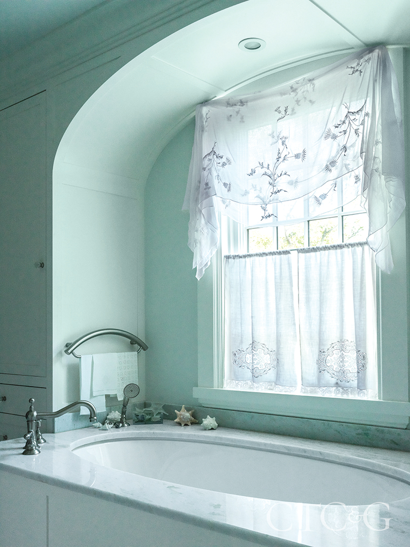 custom window treatments and green marble tub in primary bathroom