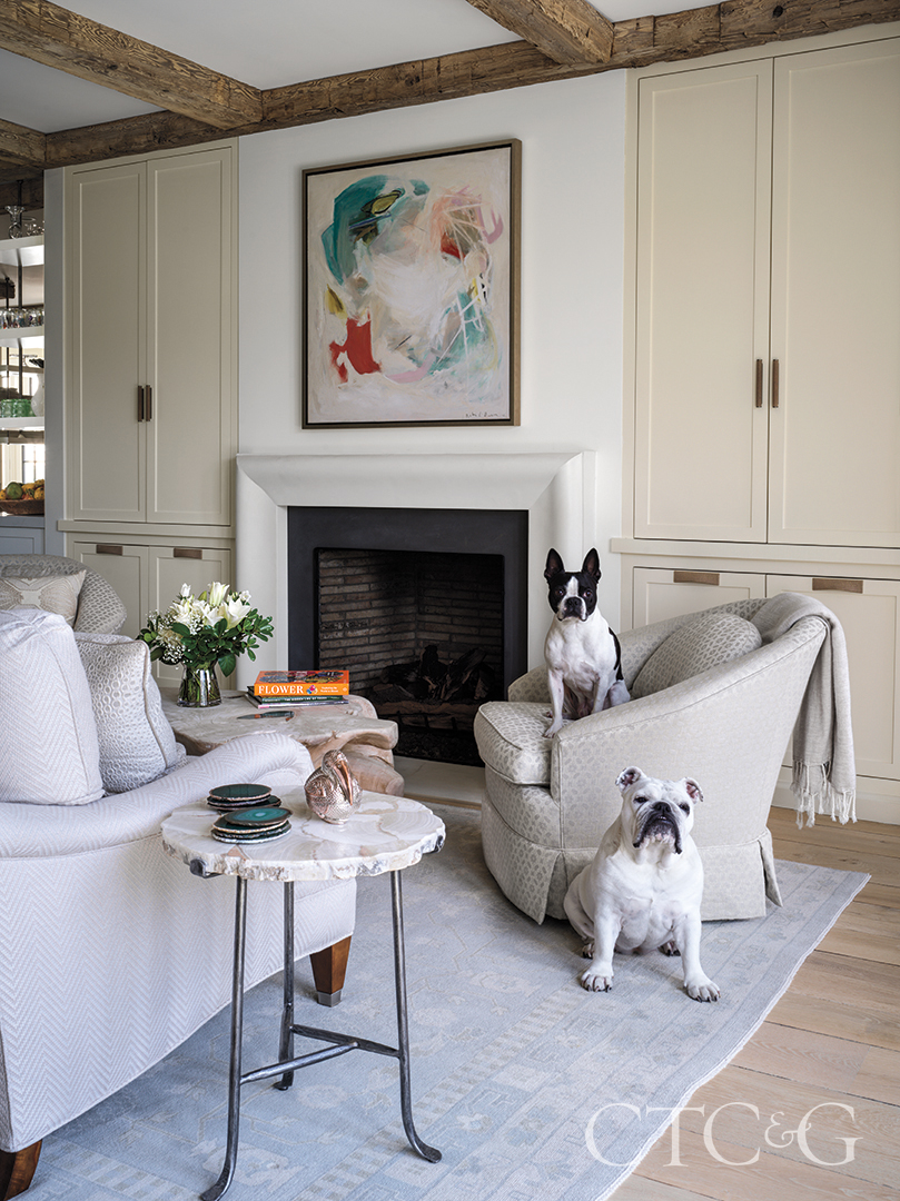 sofa and custom swivel chairs in living room; artwork above fireplace, side table and blue rug