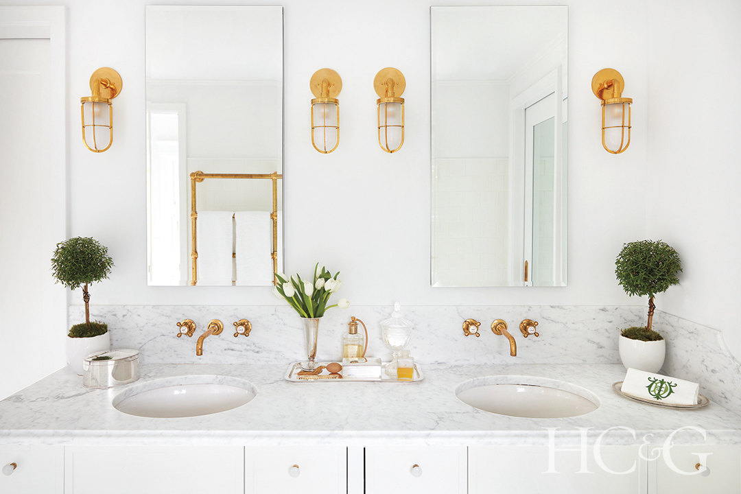 mirrored medicine cabinets and golden sconces in main bathroom