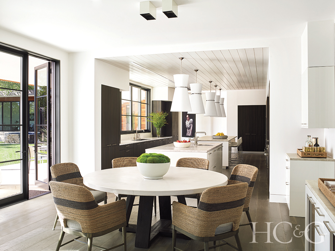 custom islands in kitchen, round concrete table, rope chairs, and cabinetry