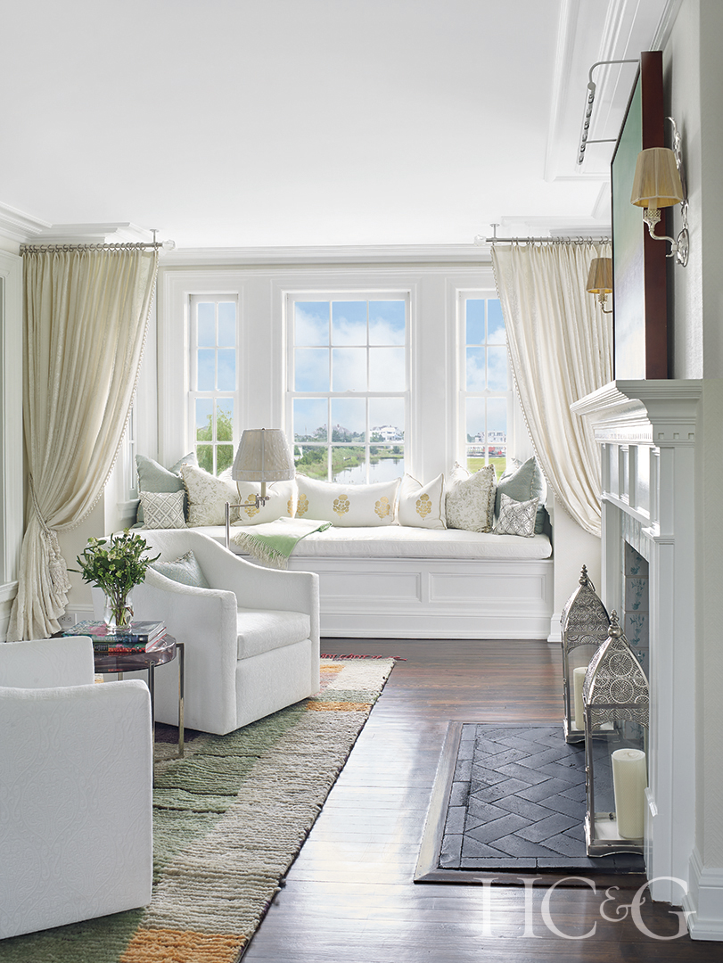 sitting room with white swivel club chairs, cream curtains, and fireplace