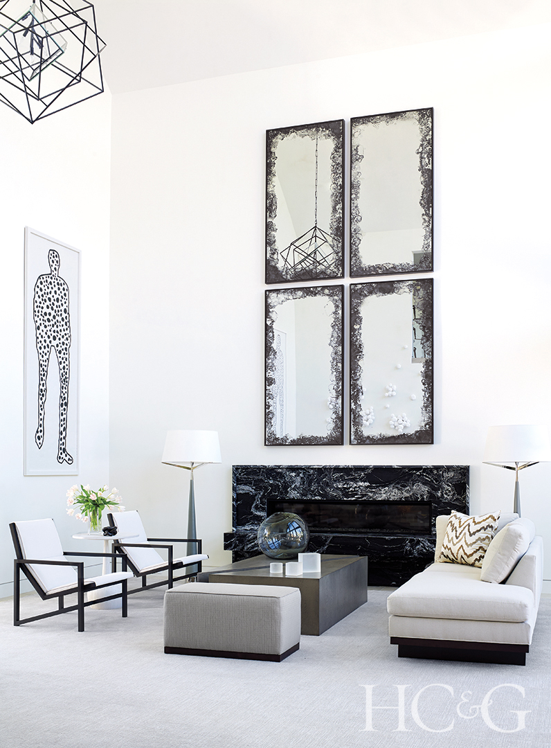 antiqued-mirror panels above a black marble fireplace in living room; armchairs, lamps and wall art