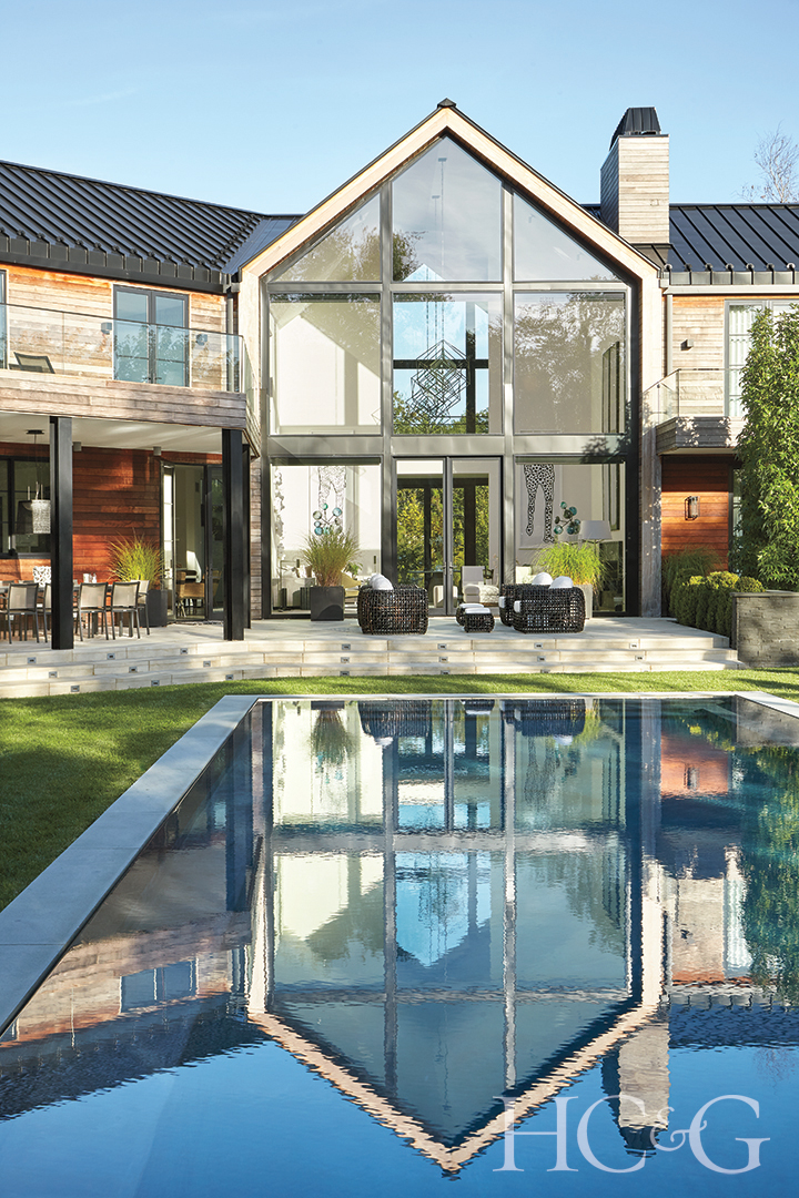 infinity-edge pool behind glass-walled double-height entry and living room