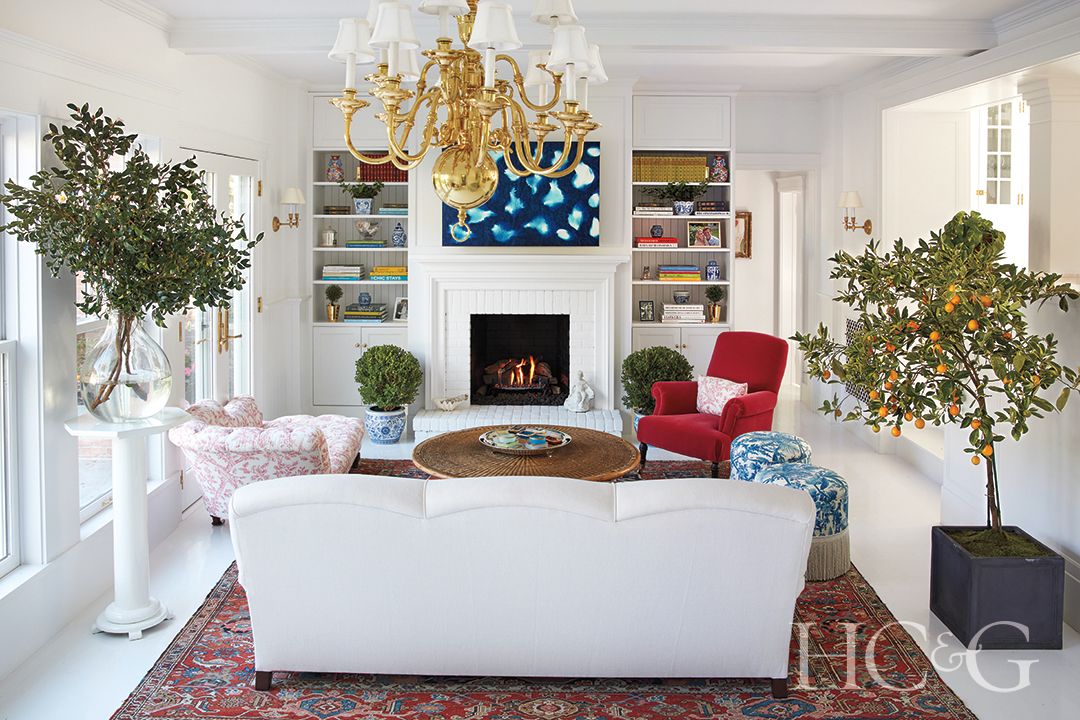 vintage rug, chaise, ottomans, and armchair; golden chandelier and fireplace