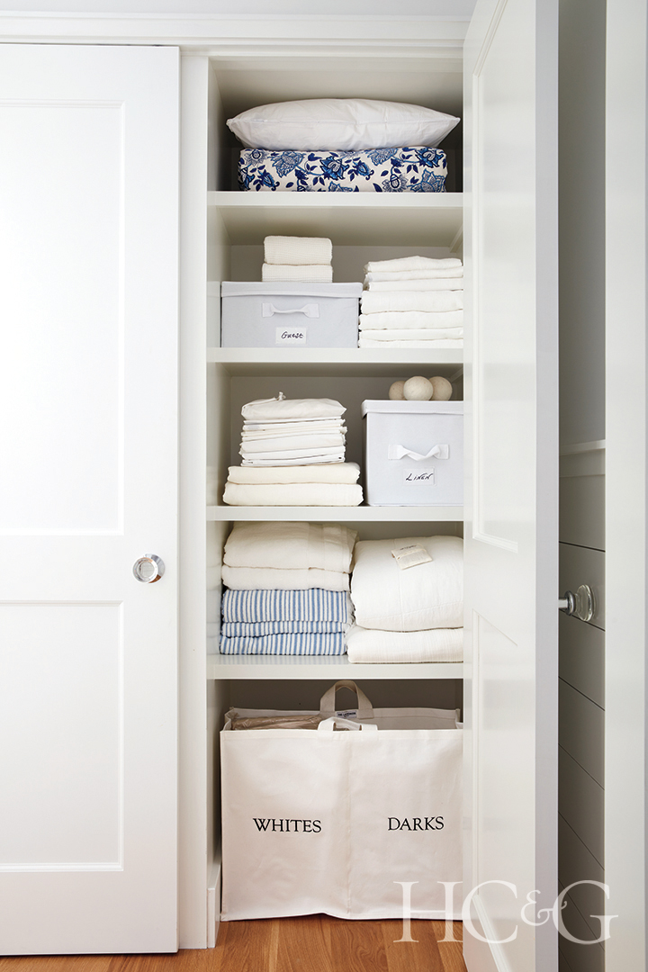 white shelves of linen closet; labeled laundry basket and organizers