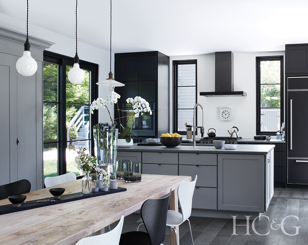 open kitchen with custom island and modern appliances; wood dining table made from antique gates