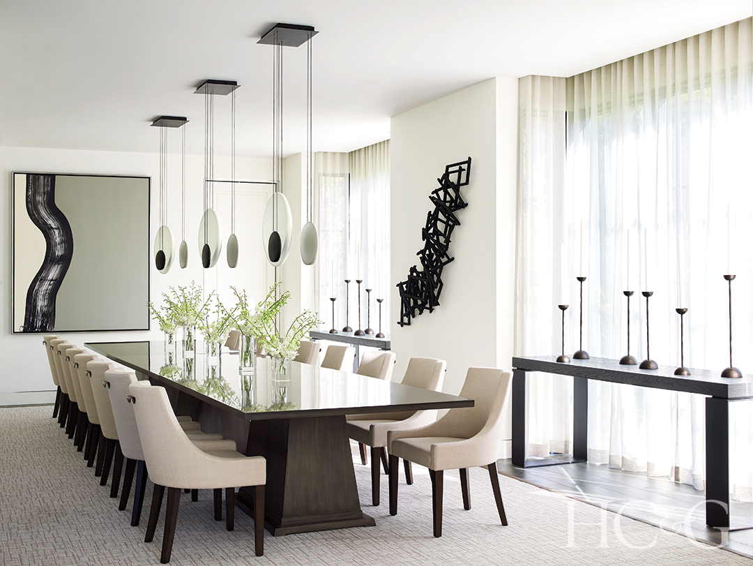 light fixtures above custom dining table; abstract painting and wall sculpture