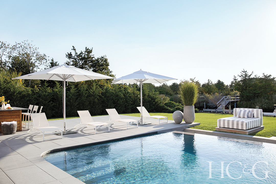 white umbrellas and chaise longues; striped daybed overlooking pool