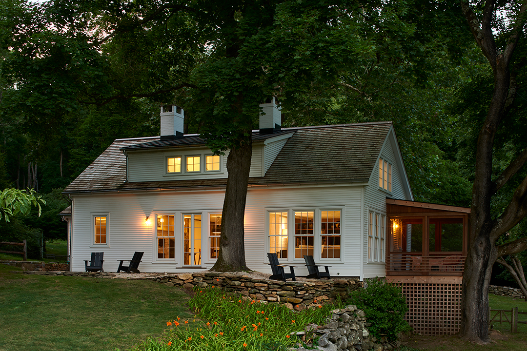 white colonial home with glowing interiors