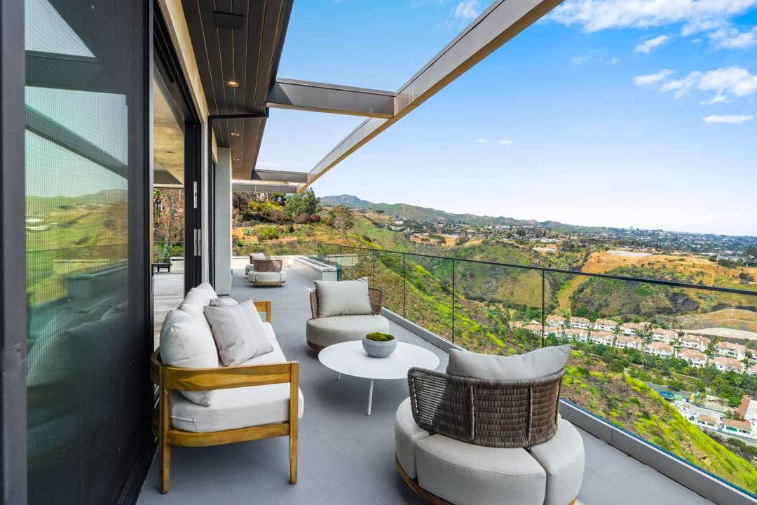 Balcony with white furniture overlooking Pacific Palisades