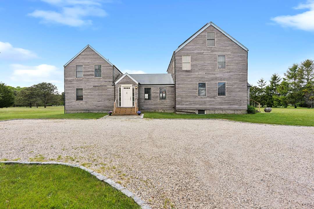 Rustic Quogue mansion with gravel driveway
